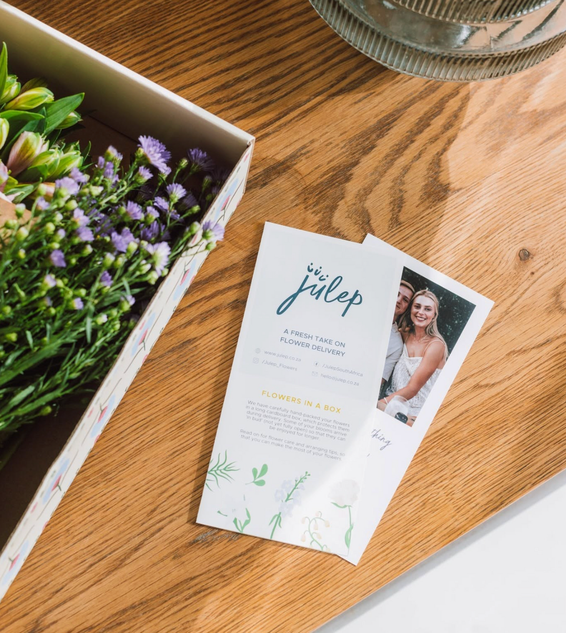 a gift card with photo sits aside a box of flowers